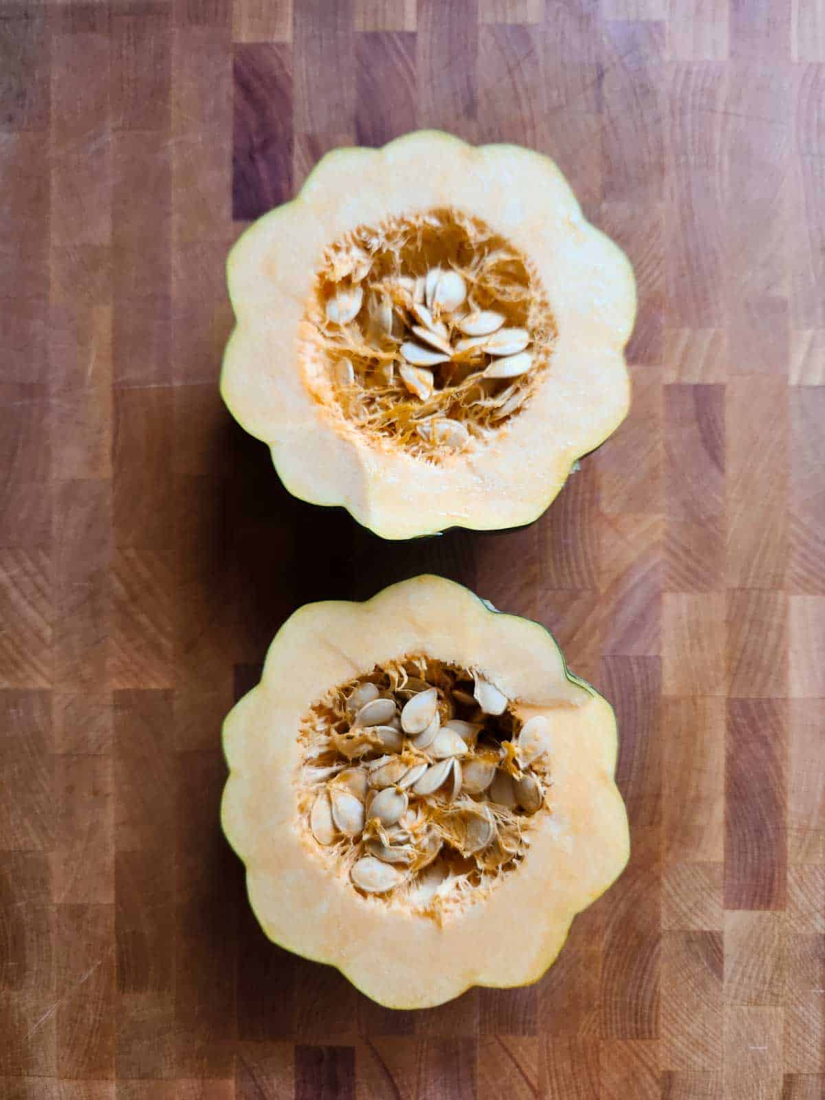 Acorn squash split in half on a cutting board.