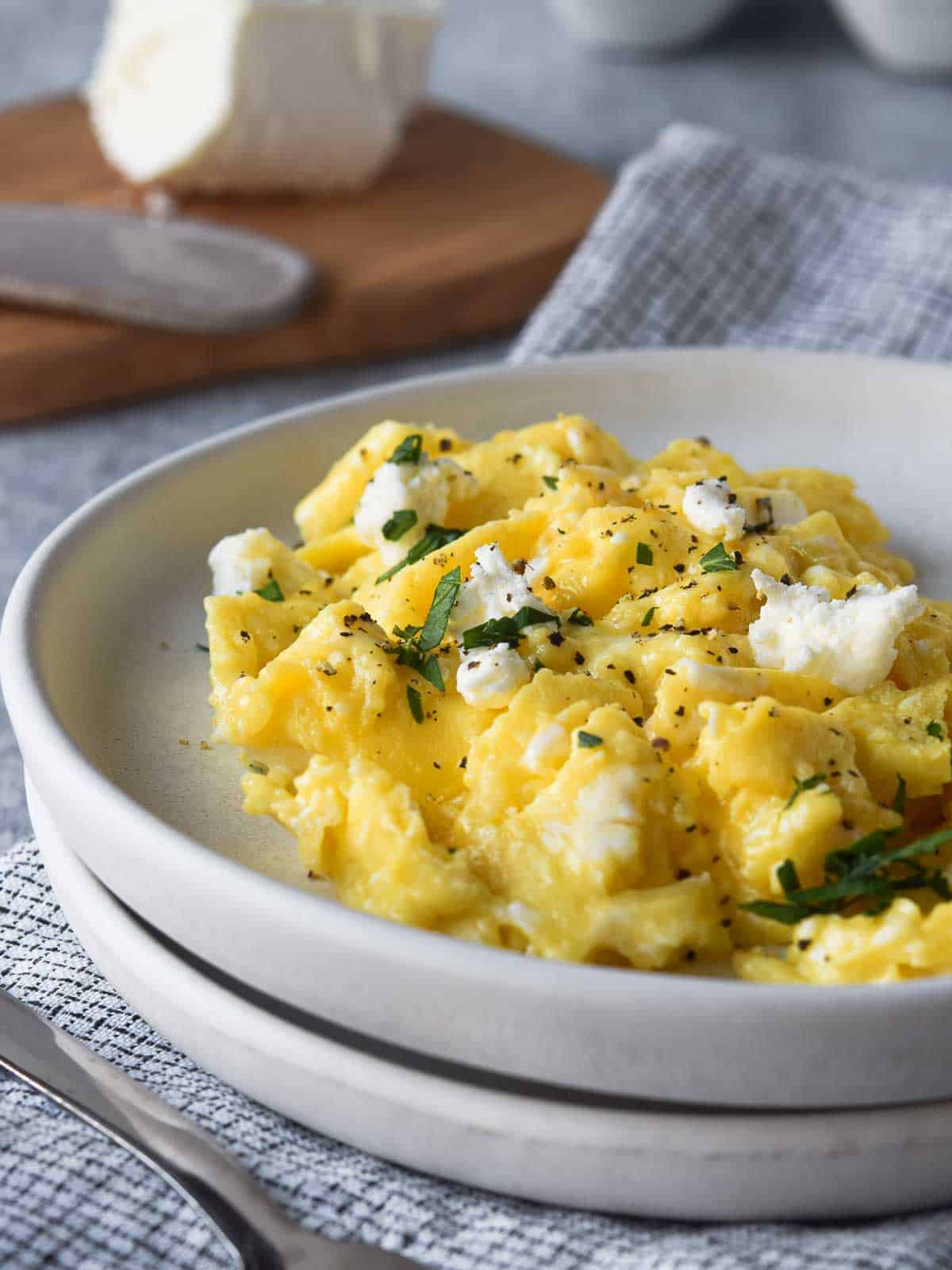 Close-up of scrambled eggs with goat cheese on a white plate.