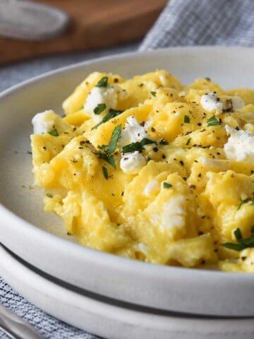 Close-up of goat cheese-scrambled eggs on a white plate.