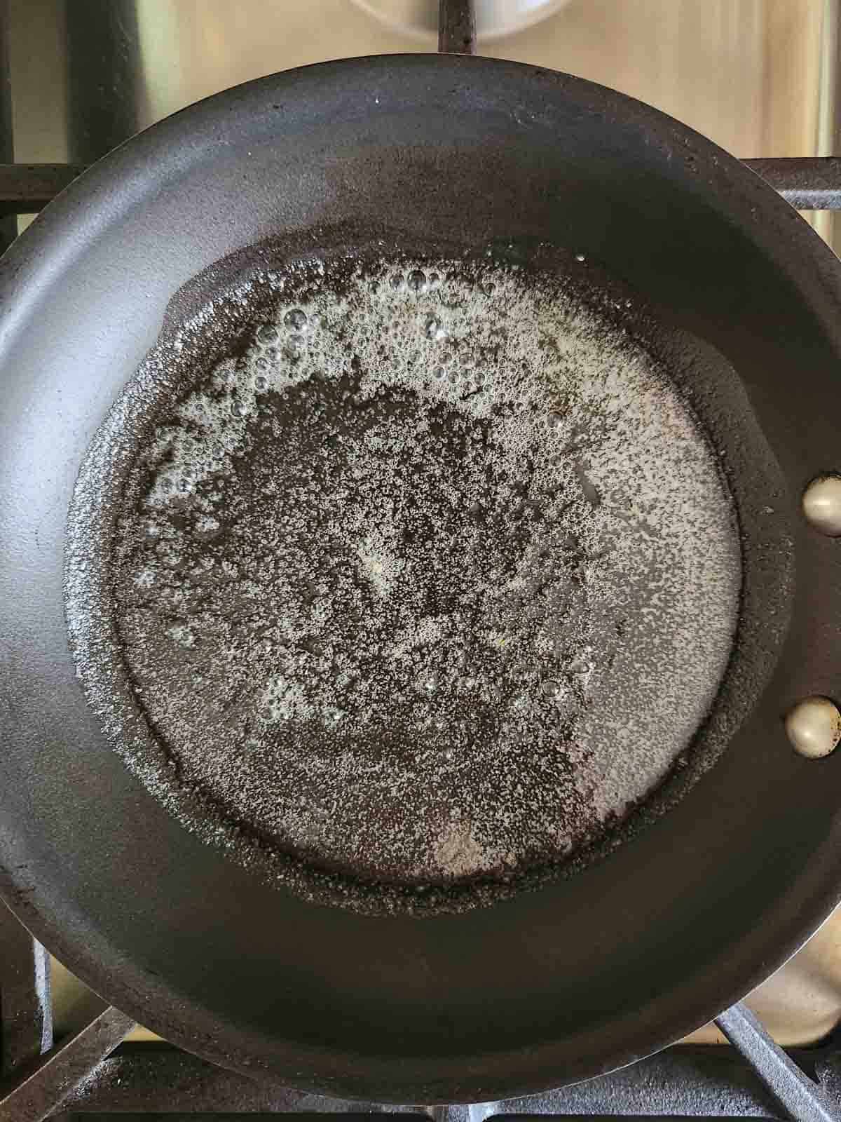 Melted butter in a small black skillet.
