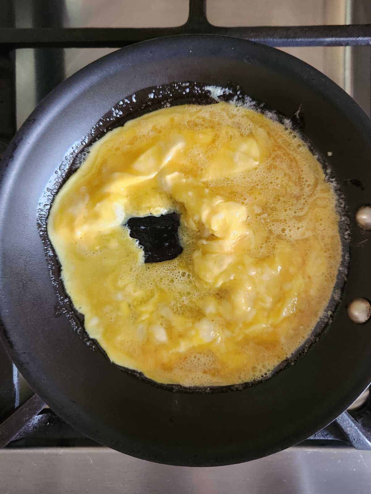 Making curds for scrambled eggs in a skillet.