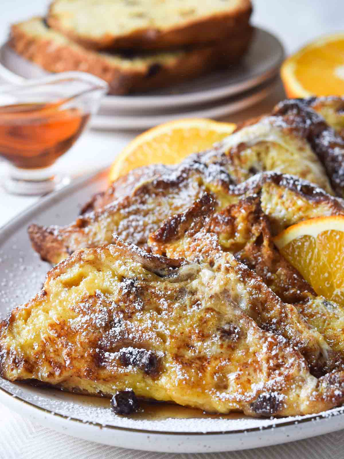 Panettone French toast on a beige platter with orange slices.