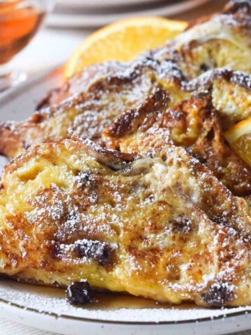 Panettone French toast on a beige platter with orange slices.
