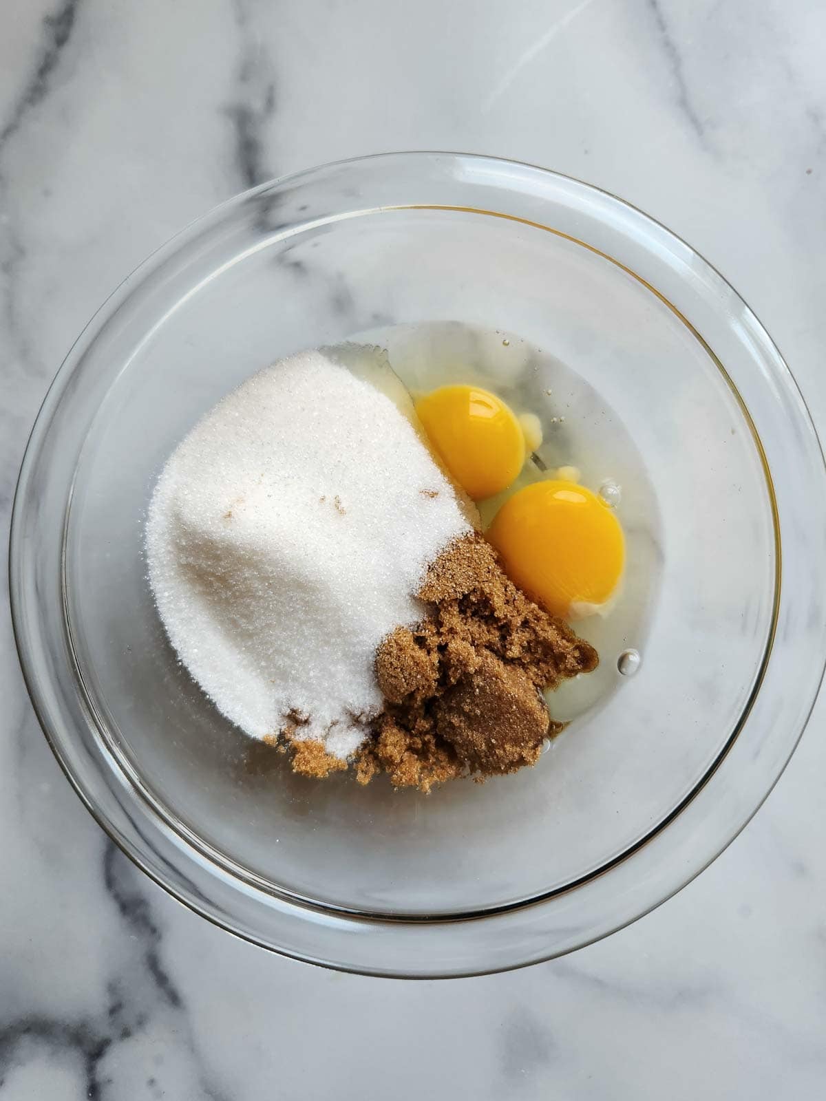 Eggs and sugar in a clear bowl.