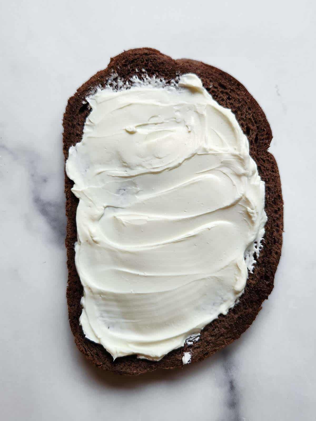 Pumpernickel bread with cream cheese on a white background.