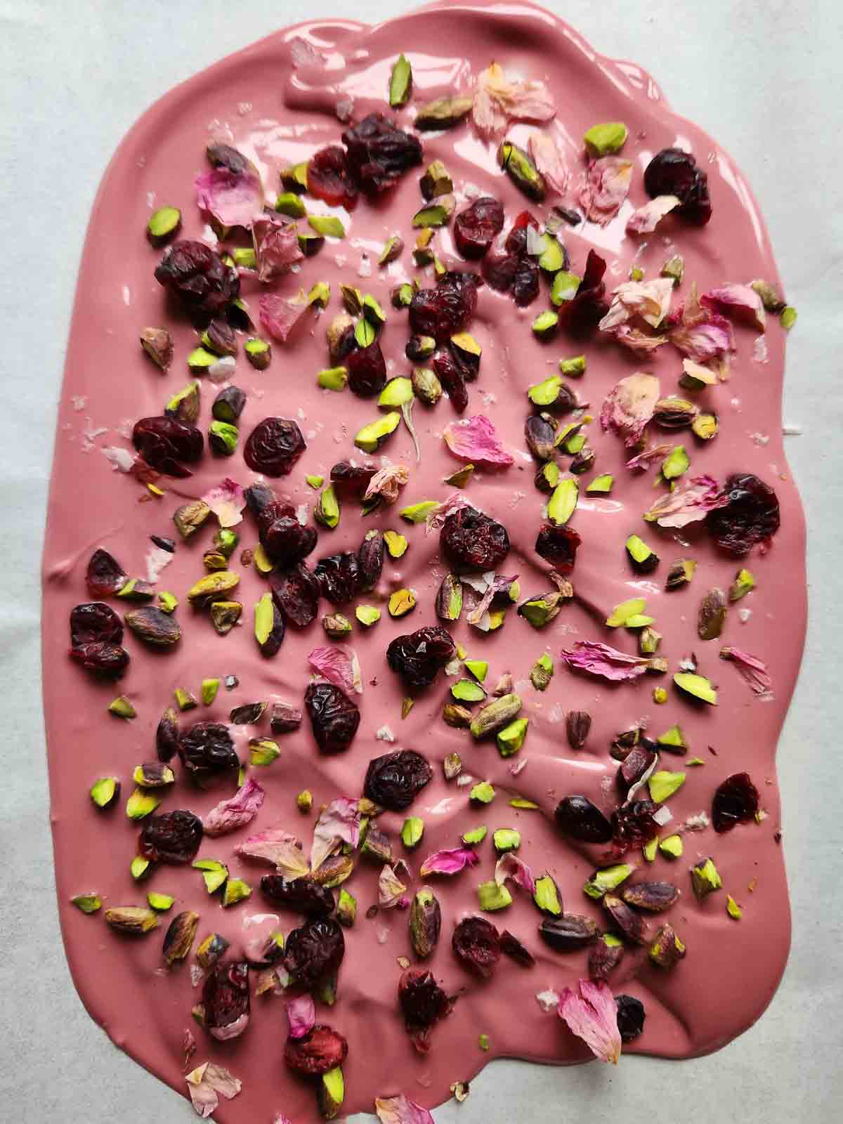 Melted ruby chocolate with toppings on parchment paper.