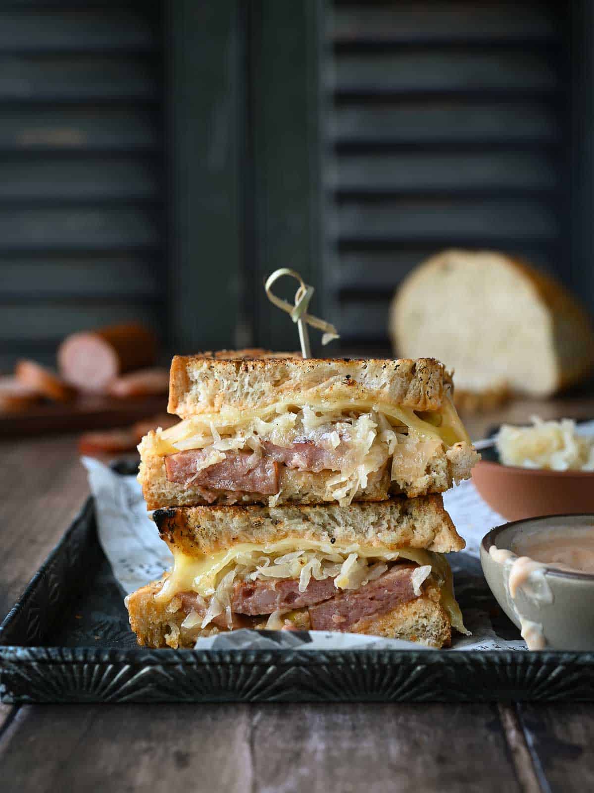 Kielbasa sandwiches stacked on top of each other with condiments on the side.