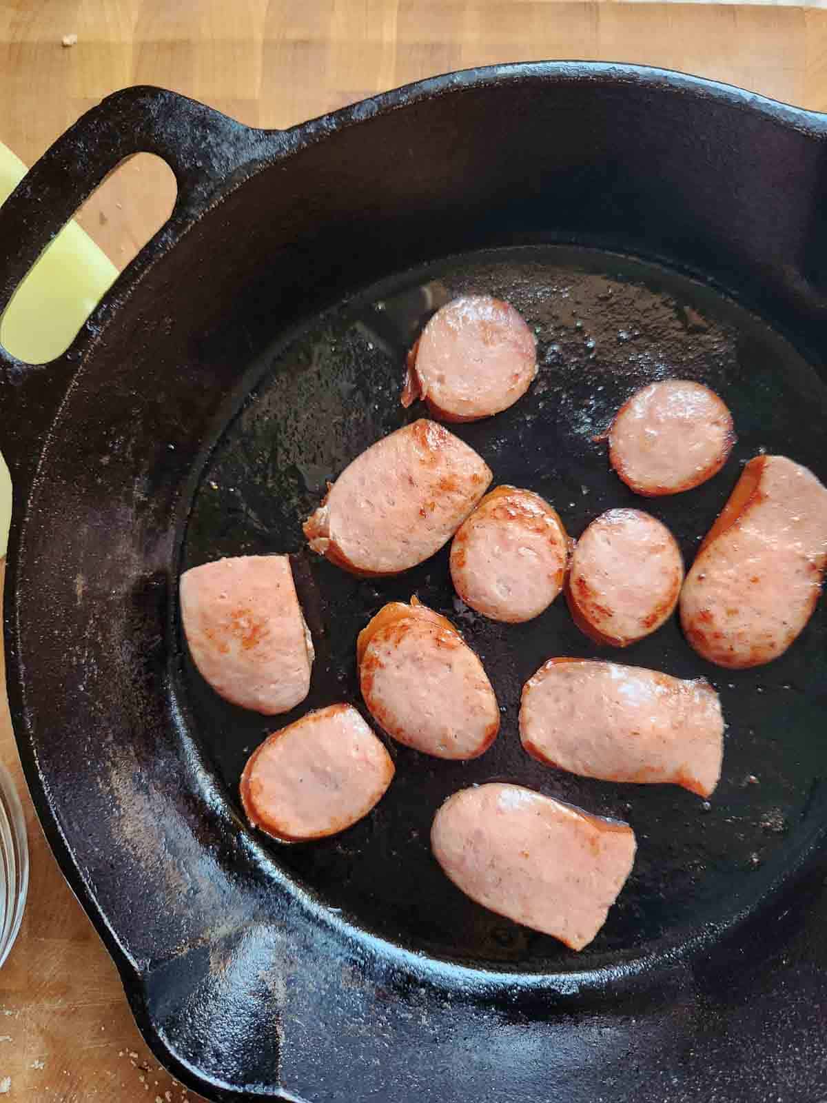 Fried kielbasa sausage in a cast iron skillet.