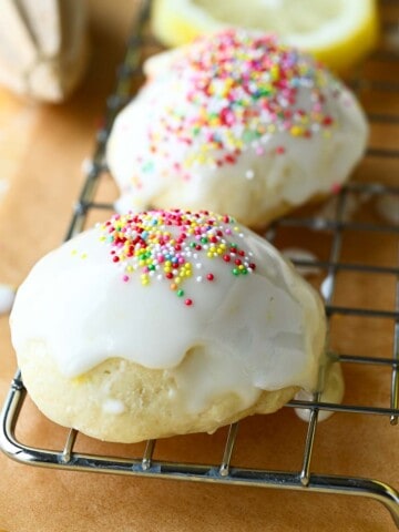 Close-up of Italian lemon drop cookies on a wire rack with multicolored sprinkles on top.