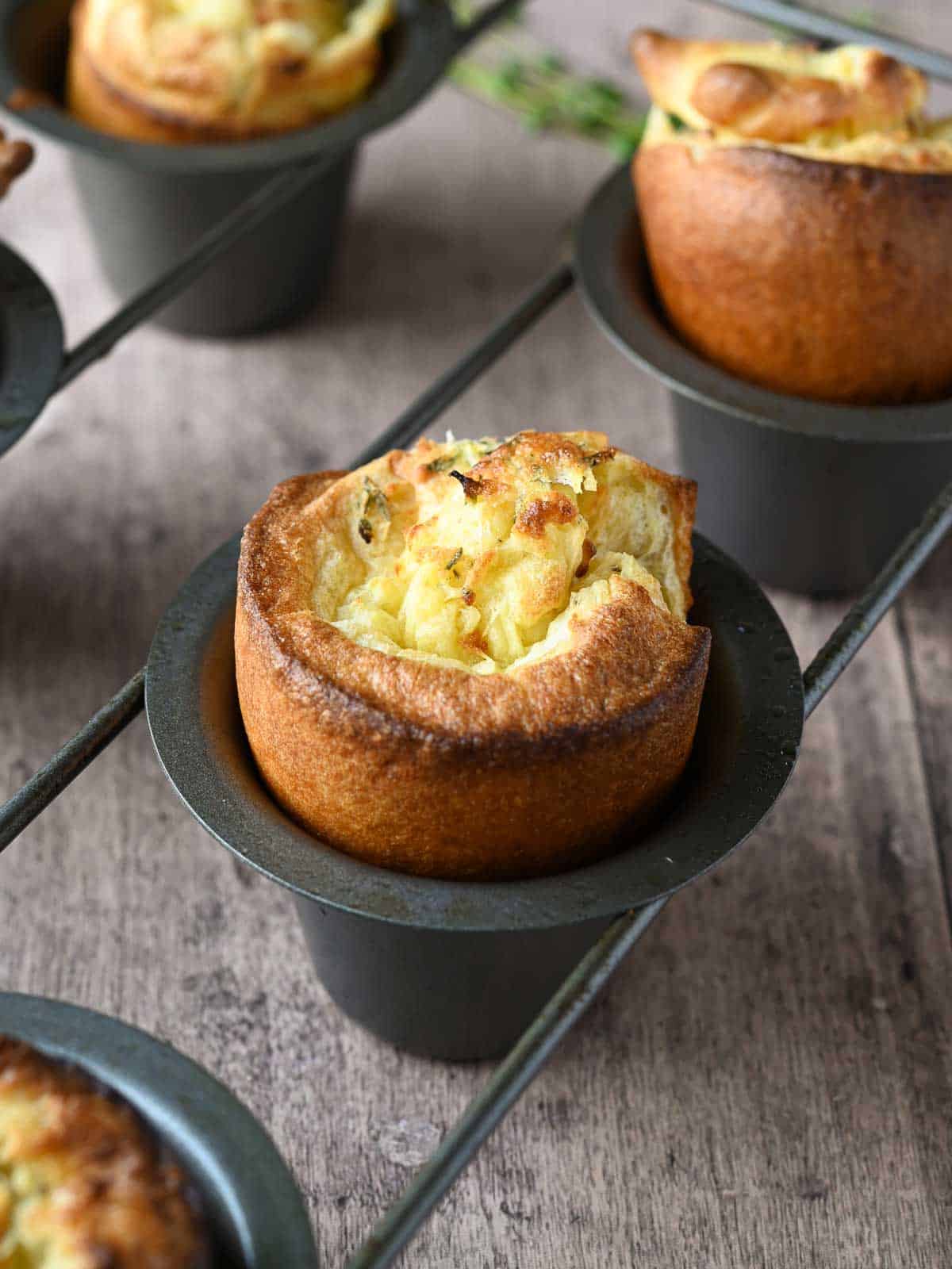 Lemon and thyme popovers in a popover pan on a wooden surface.