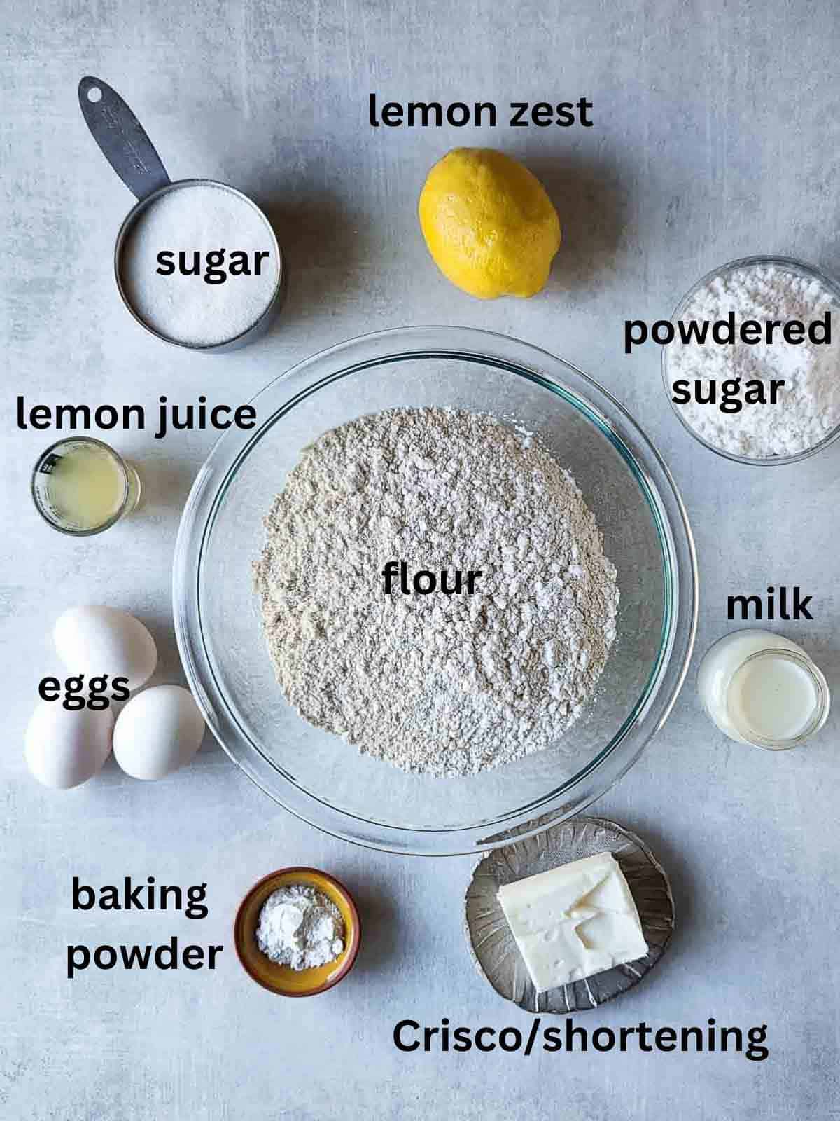 Ingredients for Italian lemon drop cookies on a grey surface.