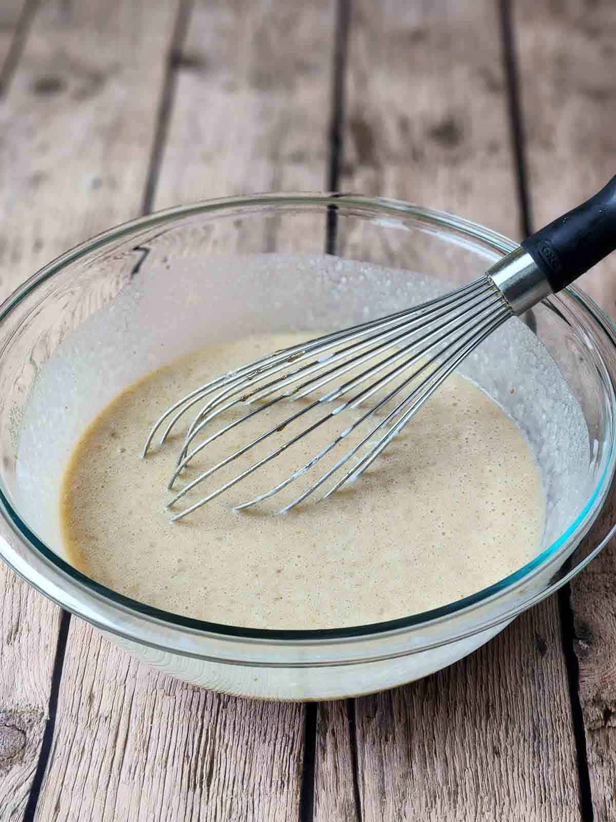Buttermilk mixture in a clear bowl with a whisk.