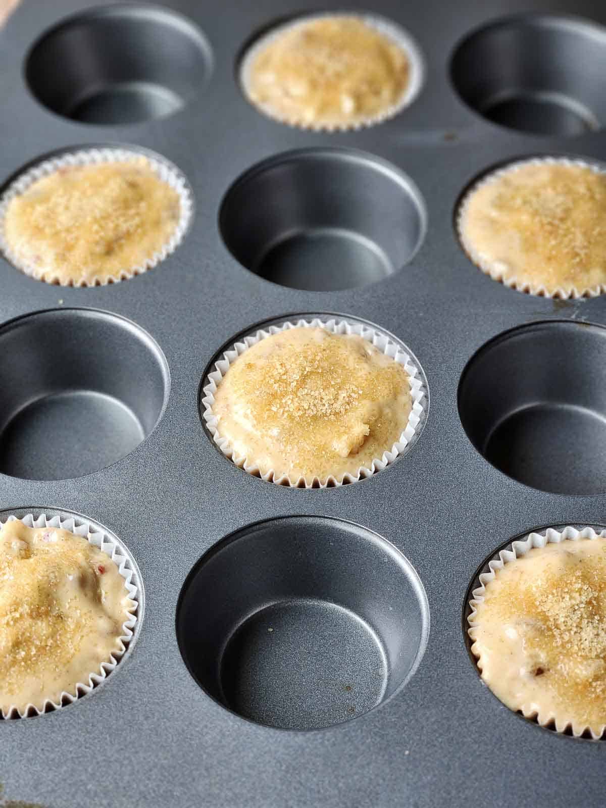 Six muffin cups filled with batter in a metal pan.