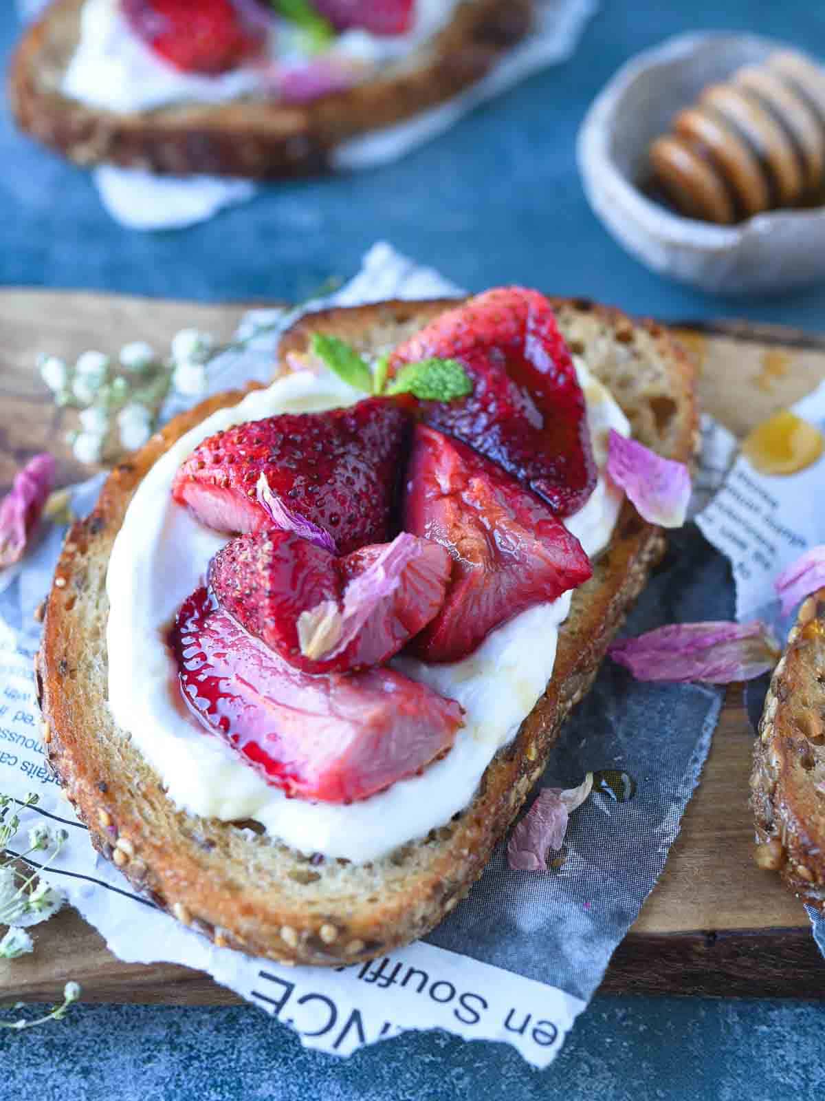 Roasted strawberries and labneh on toast over a cutting board.