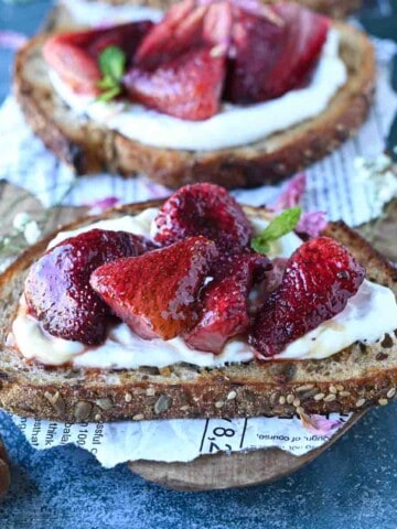 Close-up of strawberry labneh toast on a cutting board.