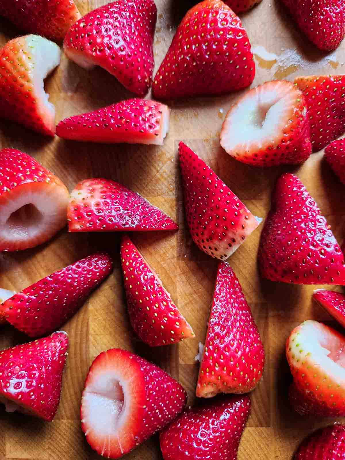 Cut strawberries on a cutting board.