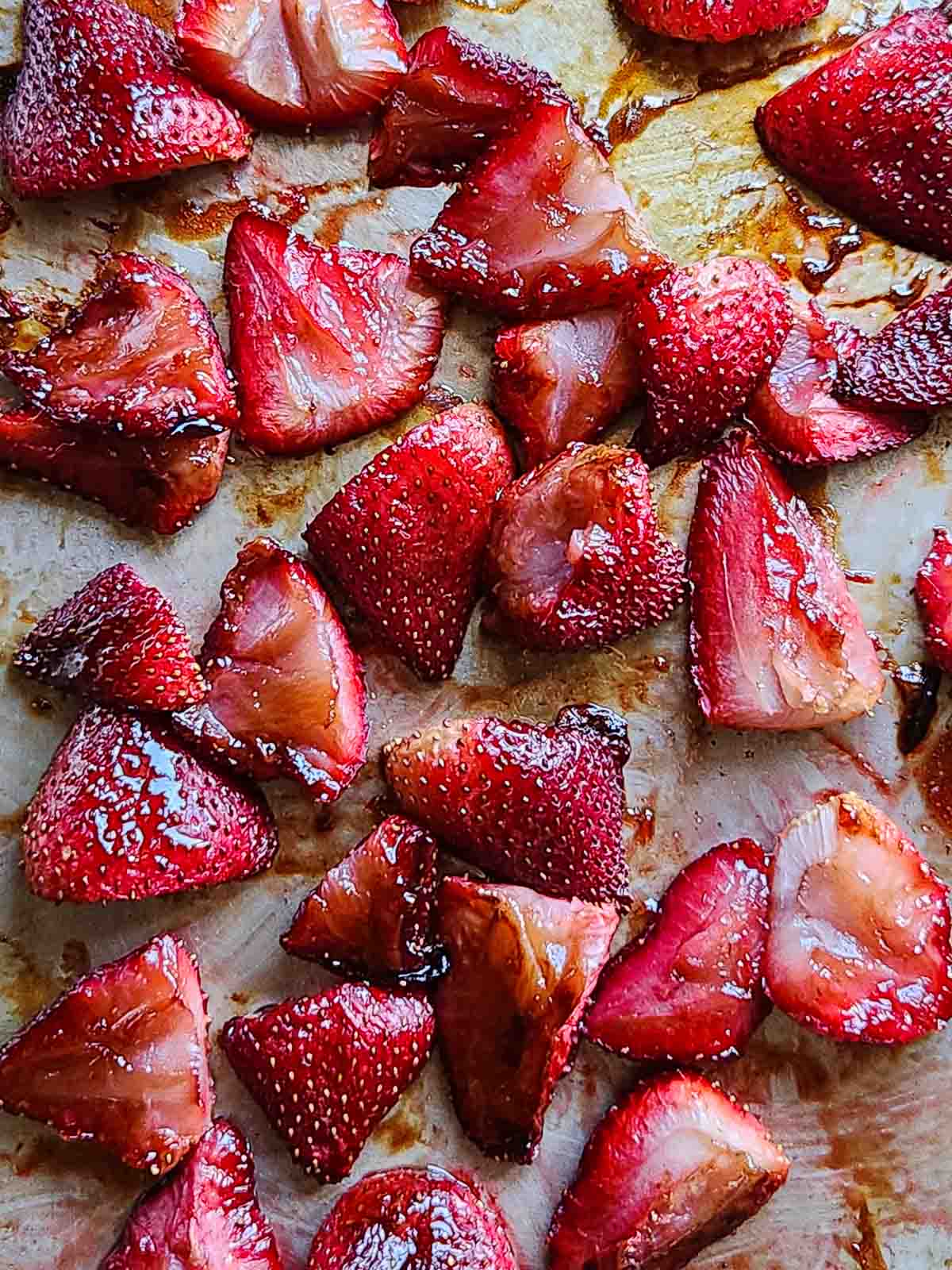 Roasted strawberries on a metal baking sheet.