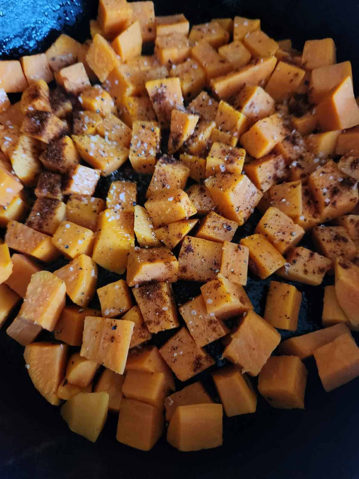 Cooking sweet potatoes and spices in a skillet.