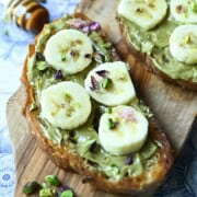 Close-up of banana-pistachio toast on a wood board.