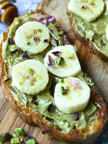 Close-up of banana-pistachio toast on a wood board.