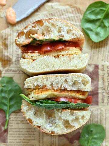 Overhead of two halloumi sandwiches on parchment paper with lettuce in the background.