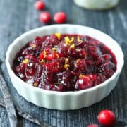 Close-up of cranberry compote in a white bowl with orange zest.