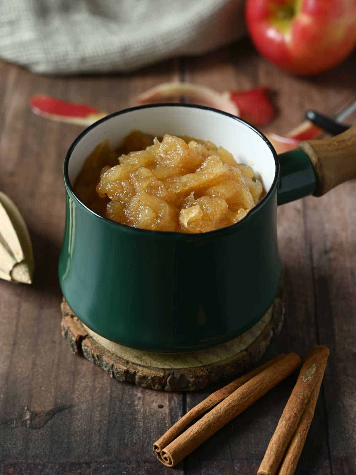 Applesauce in a small green pot on a wood table.