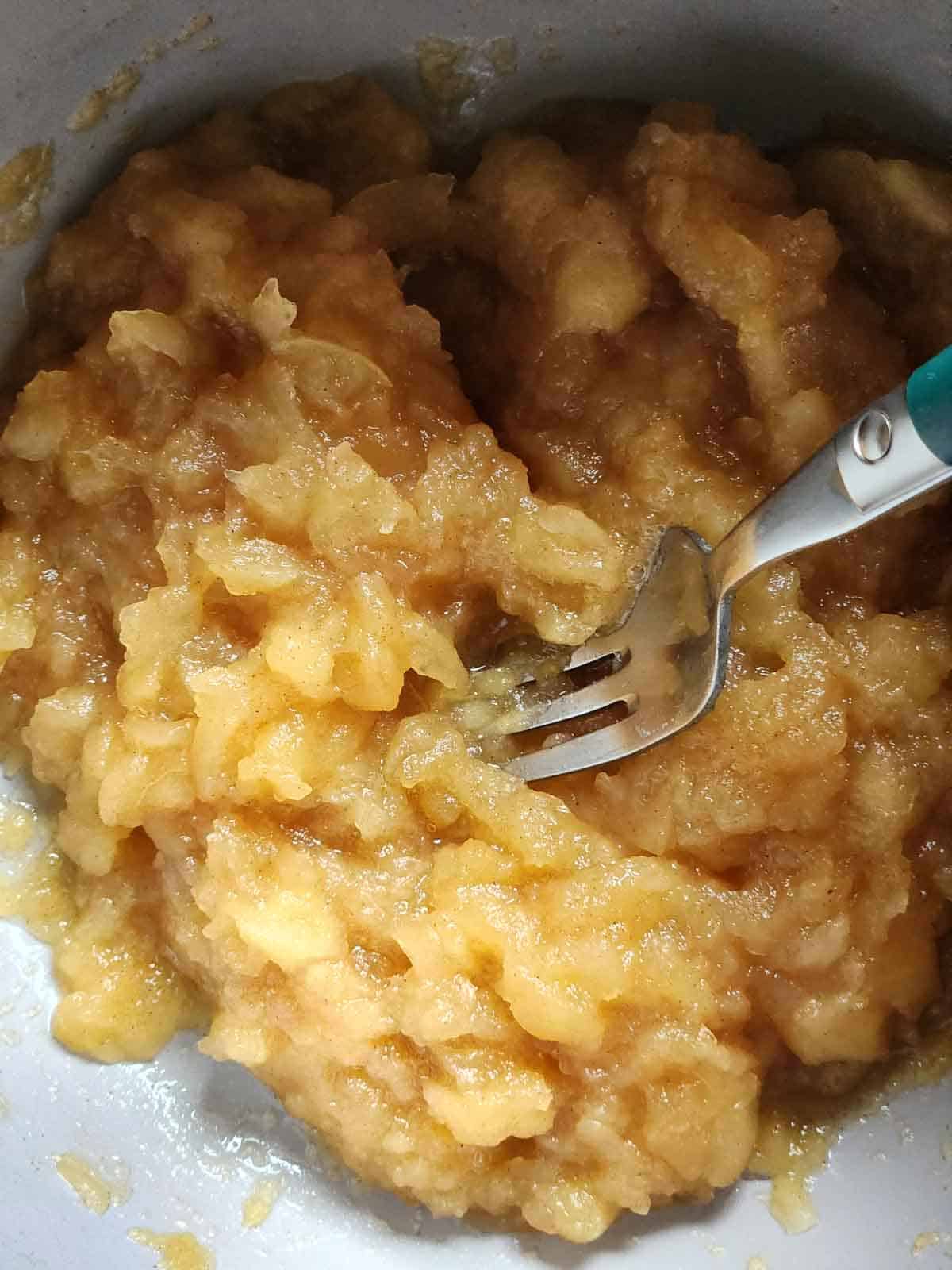 A fork in a pot after mashing apples for applesauce.