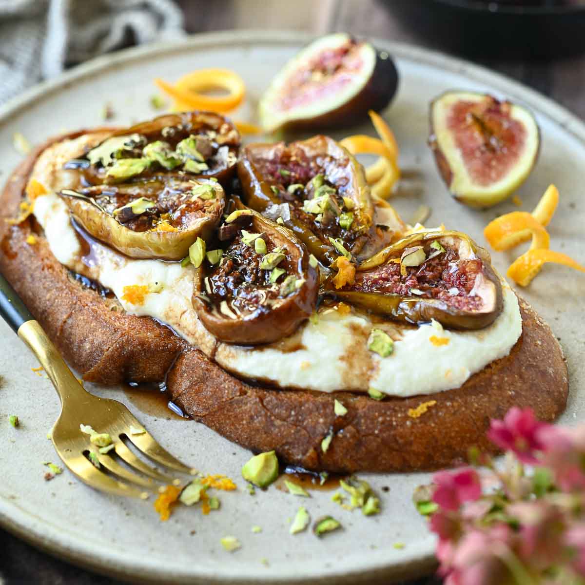 Toast with roasted figs and ricotta on top on a white plate.