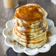 Close-up of pancakes on a beige plate with brown sugar syrup.