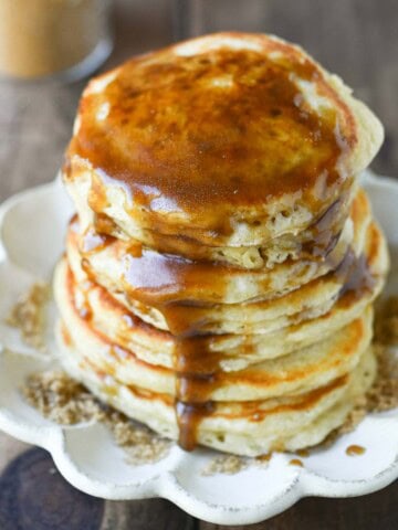 Close-up of pancakes on a beige plate with brown sugar syrup.