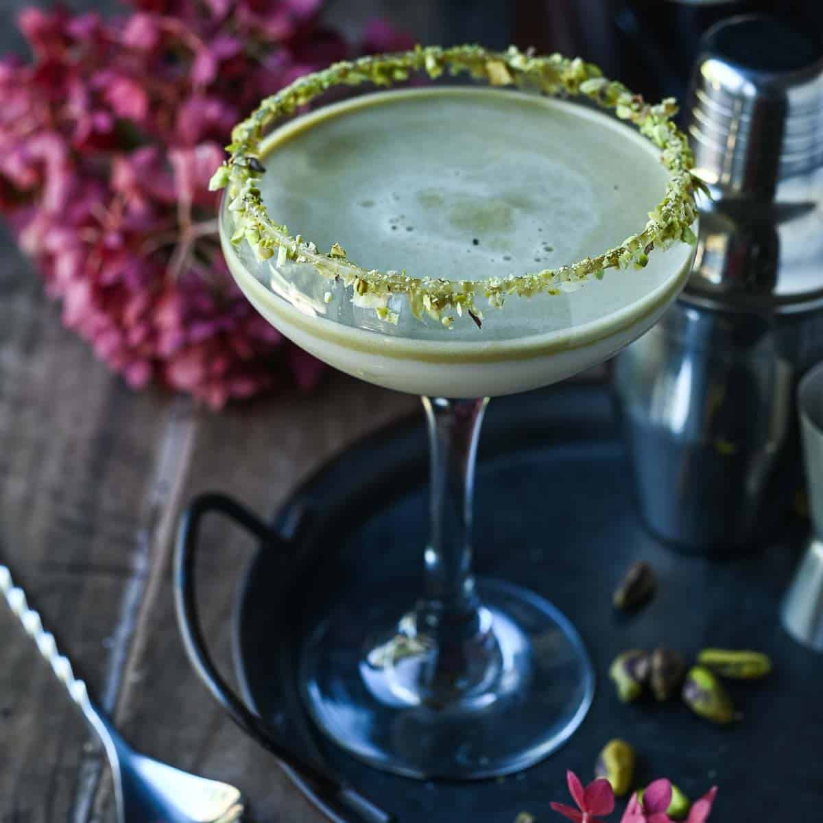 Martini on a black tray with pink flowers next to it.