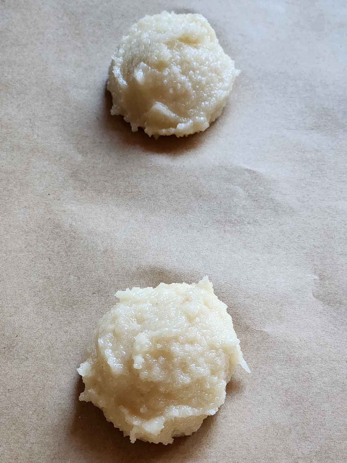 Scoops of cookie batter on parchment paper.
