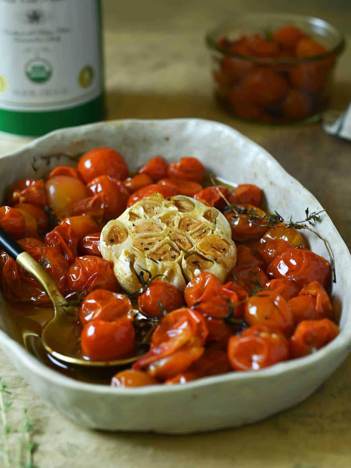 A bowl of cherry tomatoes in oil with garlic.