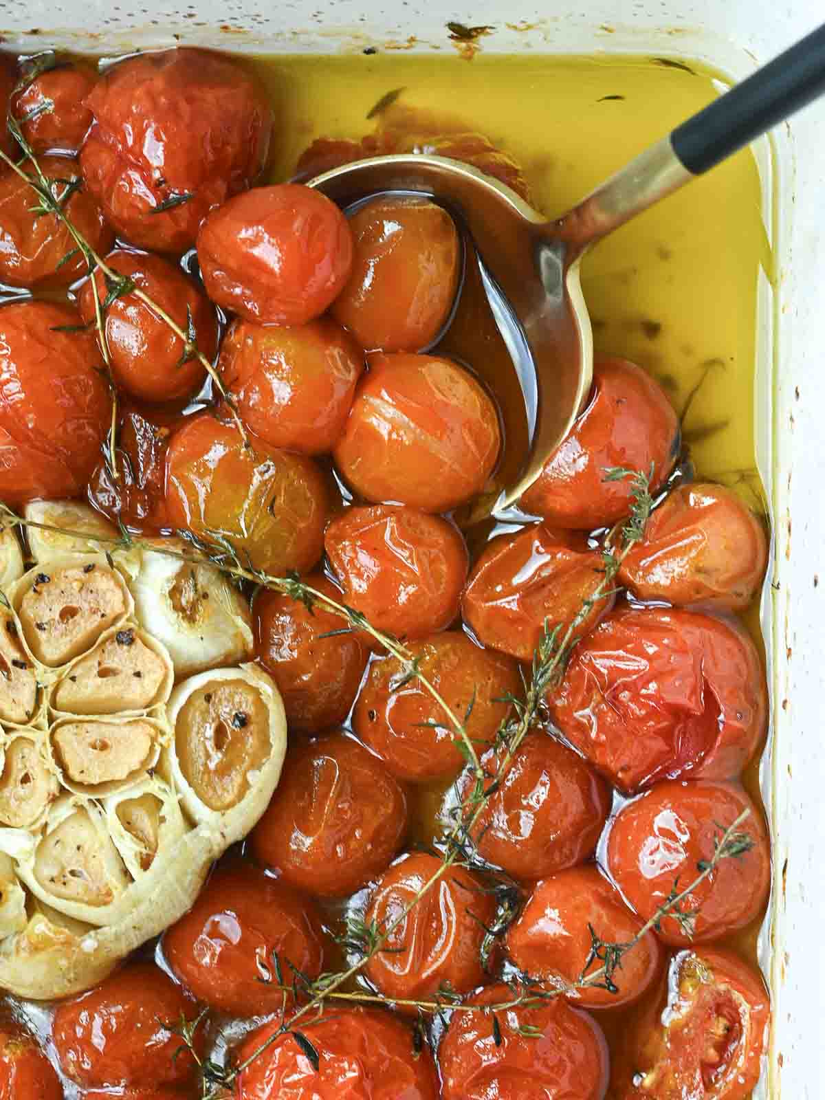 Tomato confit in a baking dish with oil and garlic.