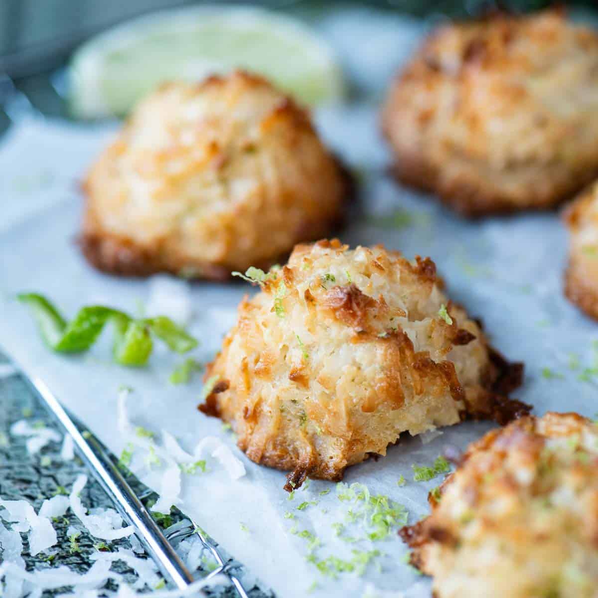 Coconut macaroons on a parchment paper with lime zest on top.