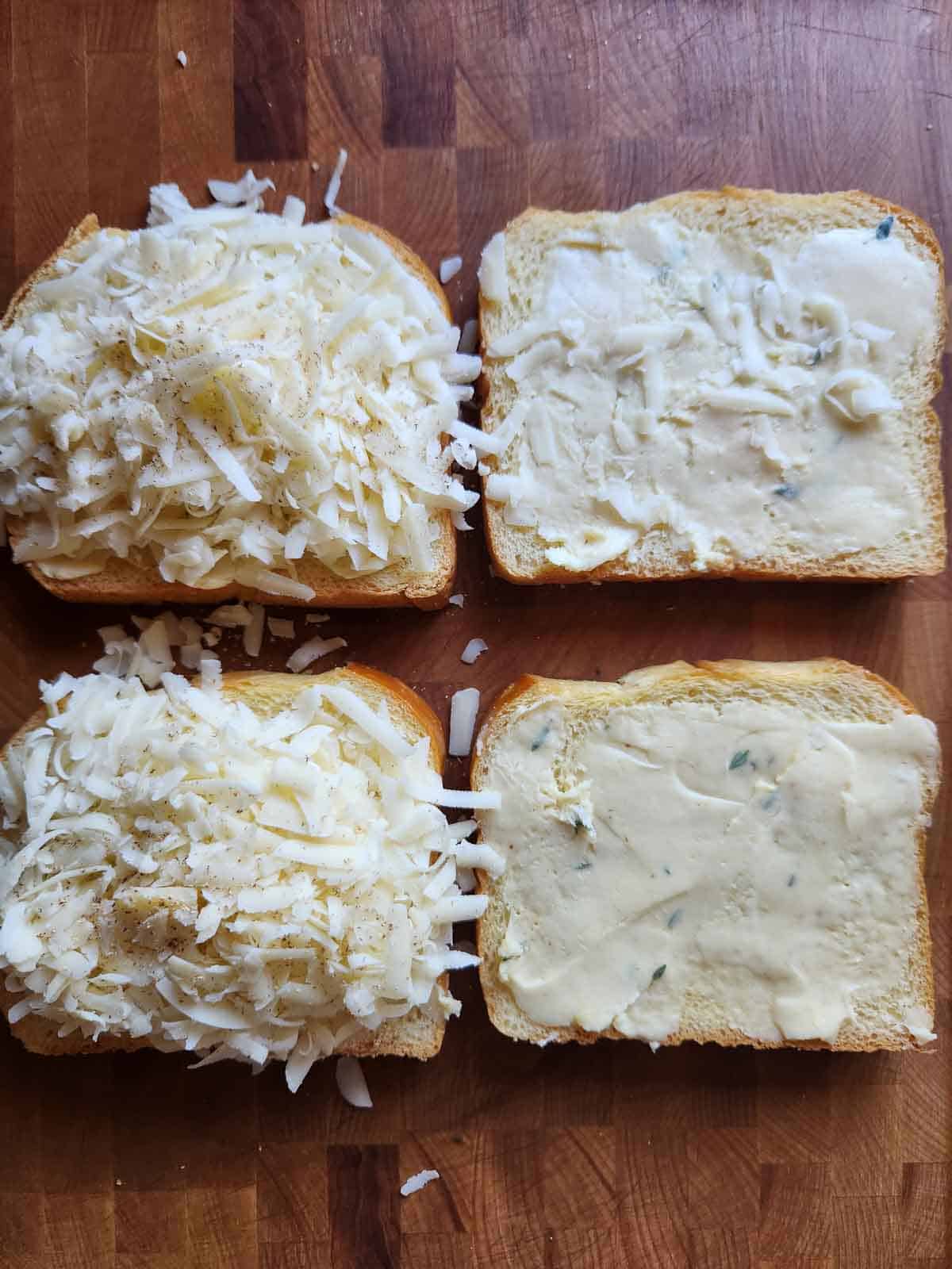 Four slices of bread on a cutting board topped with shredded cheese.