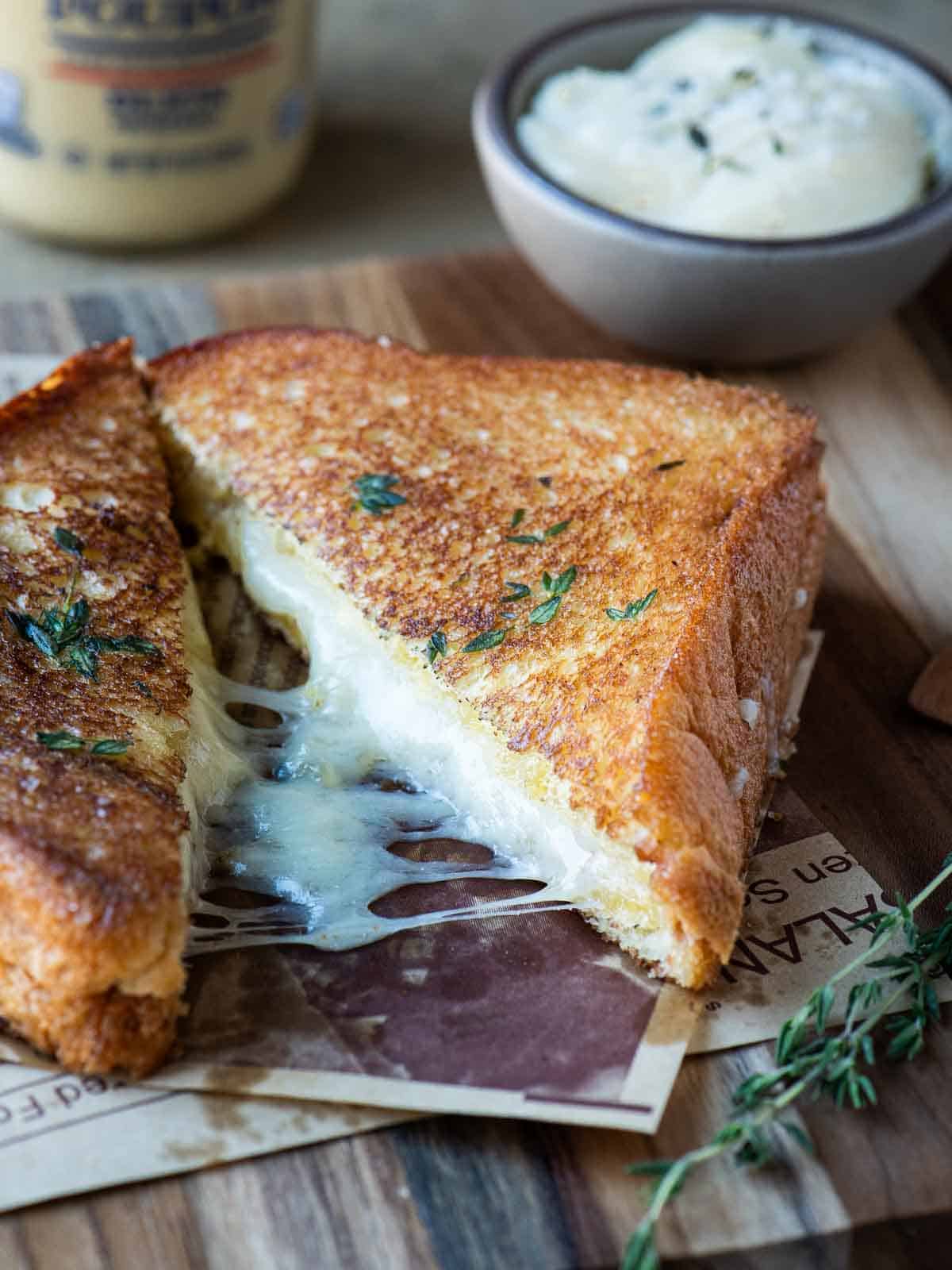 Angled view of 2 halves of a melted grilled cheese on a wood surface.