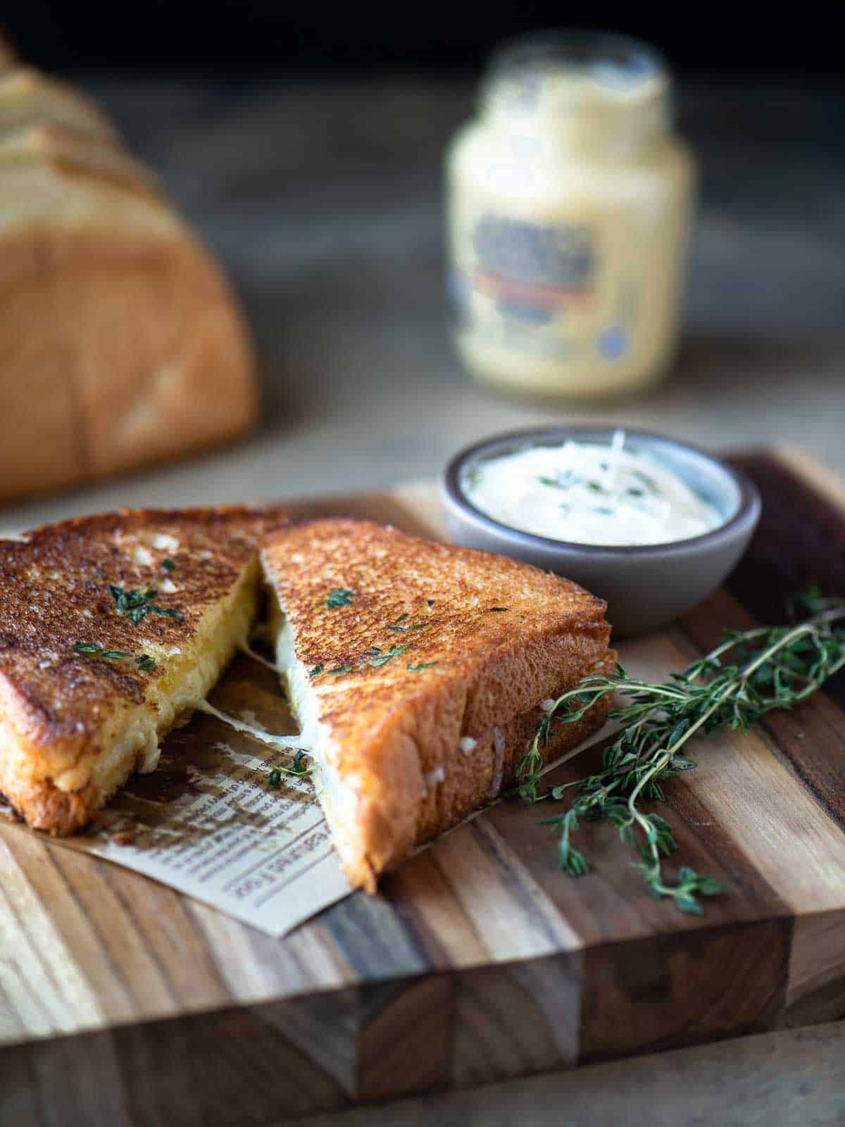 Grilled cheese sandwiches cut in half on a wood board.