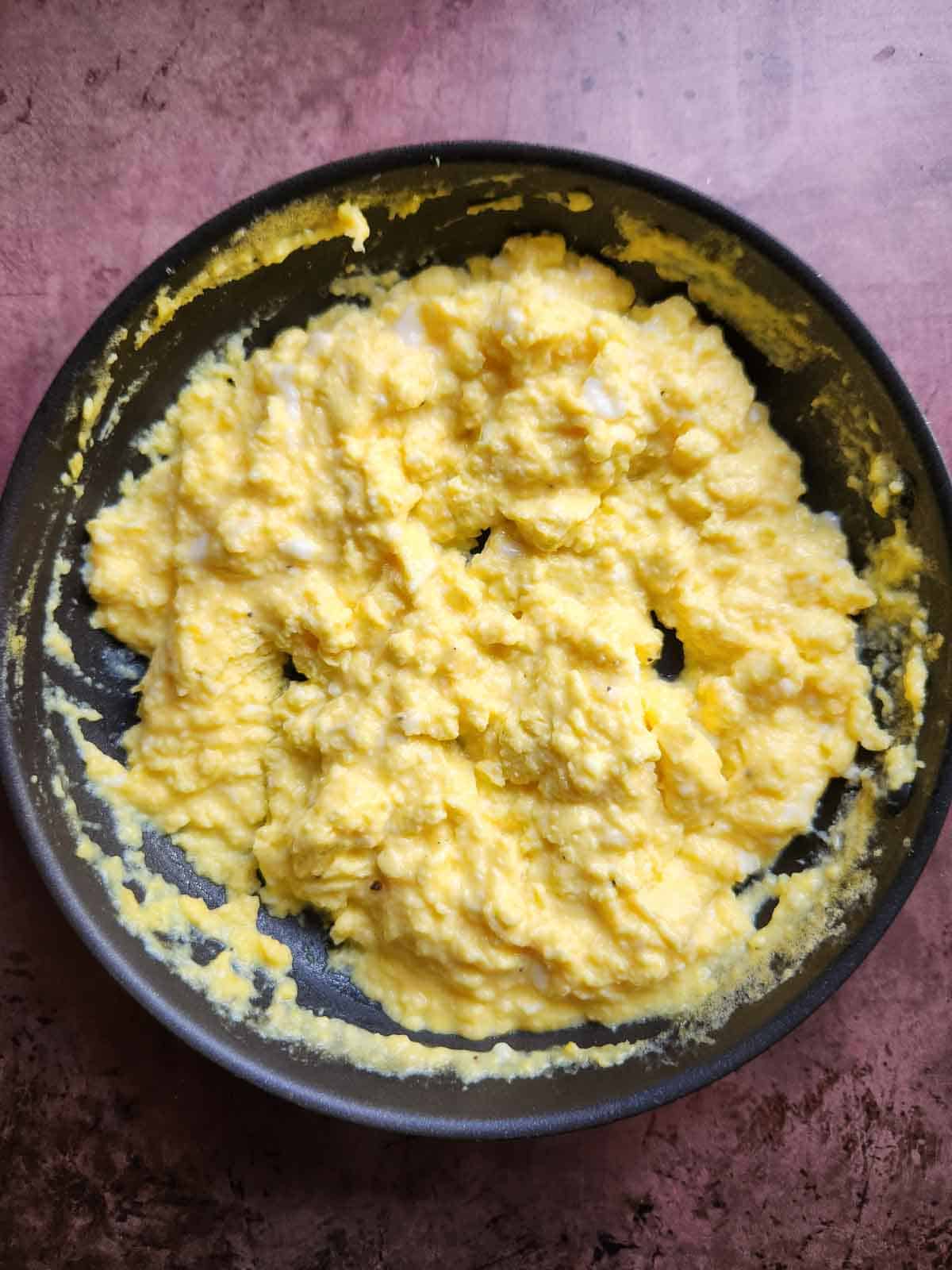 Cooked scrambled eggs in a pan.