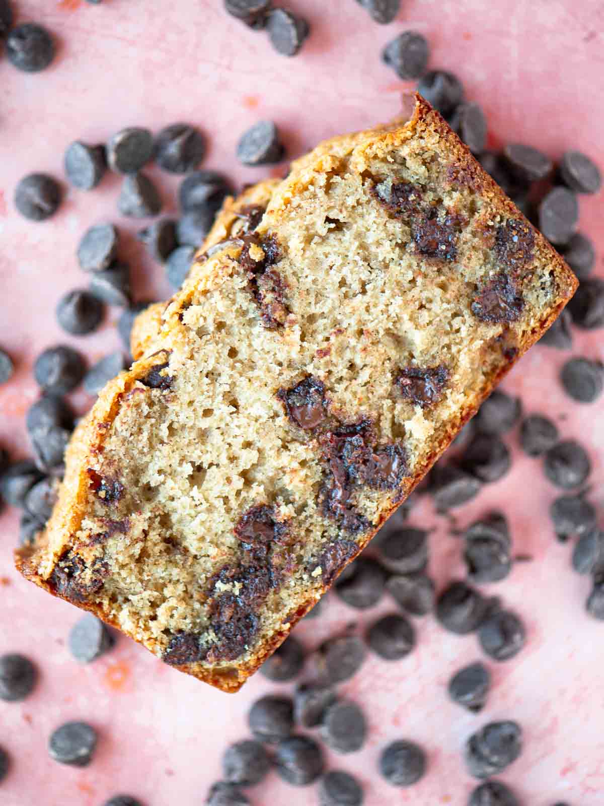 Overhead showing a slice of chocolate chip cake over chocolate chips.