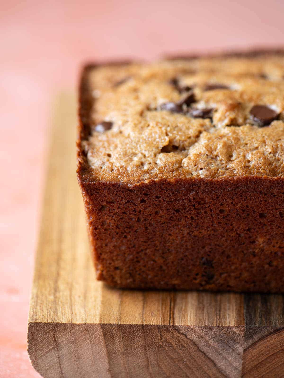 Side view of a chocolate chip loaf on a wood board.