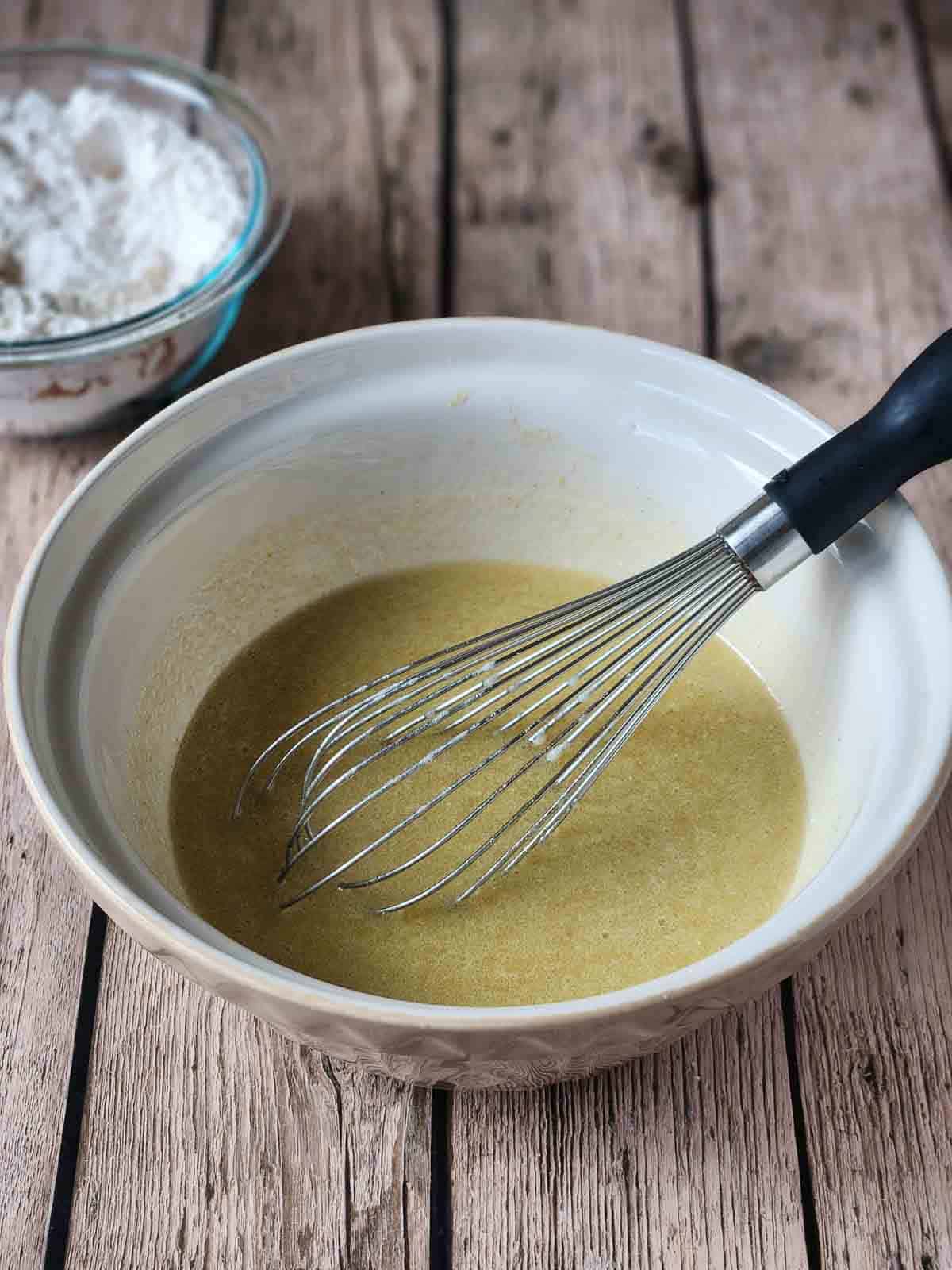 Wet ingredients in a mixing bowl with a whisk.