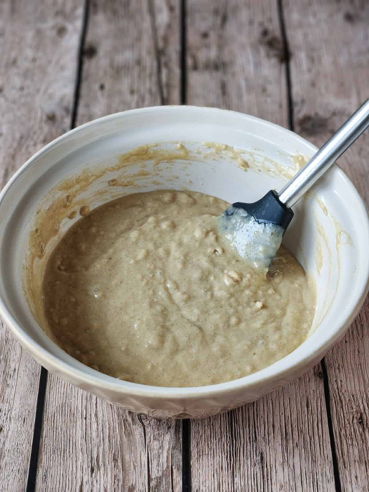 Cake batter in a beige bowl with a spatula in it.