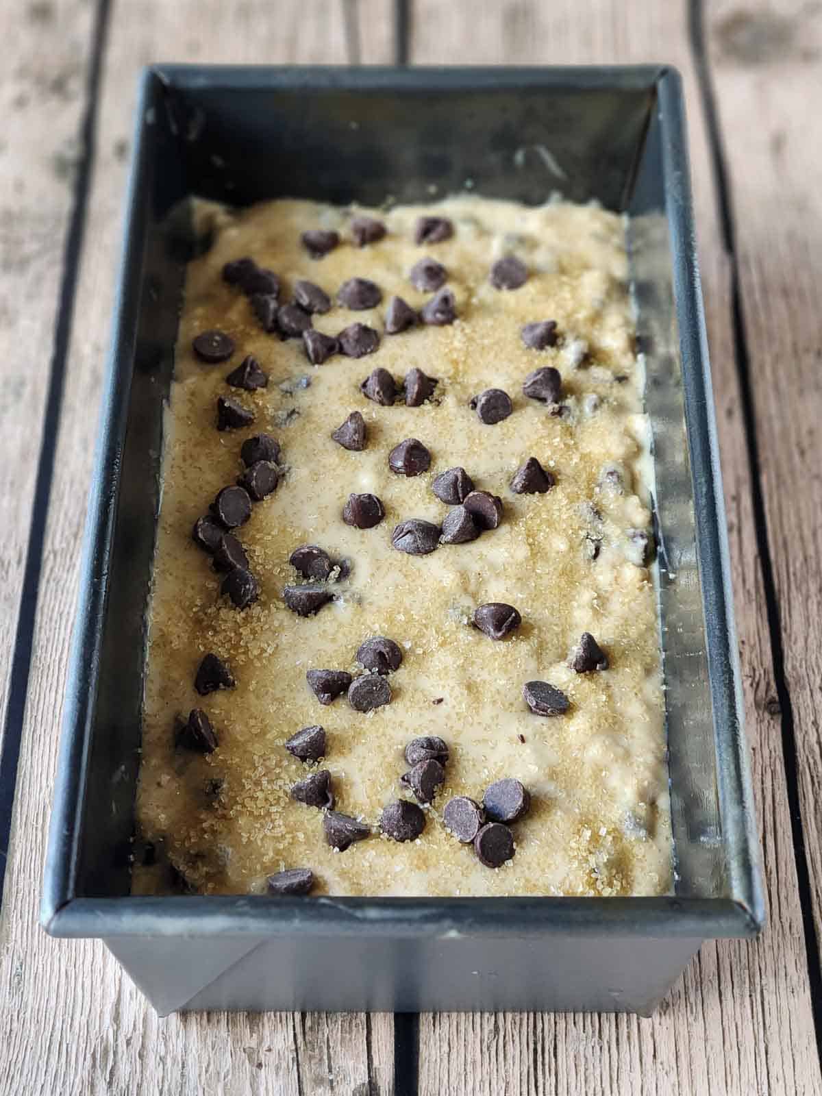Prepared batter in a metal loaf pan on a wood surface.