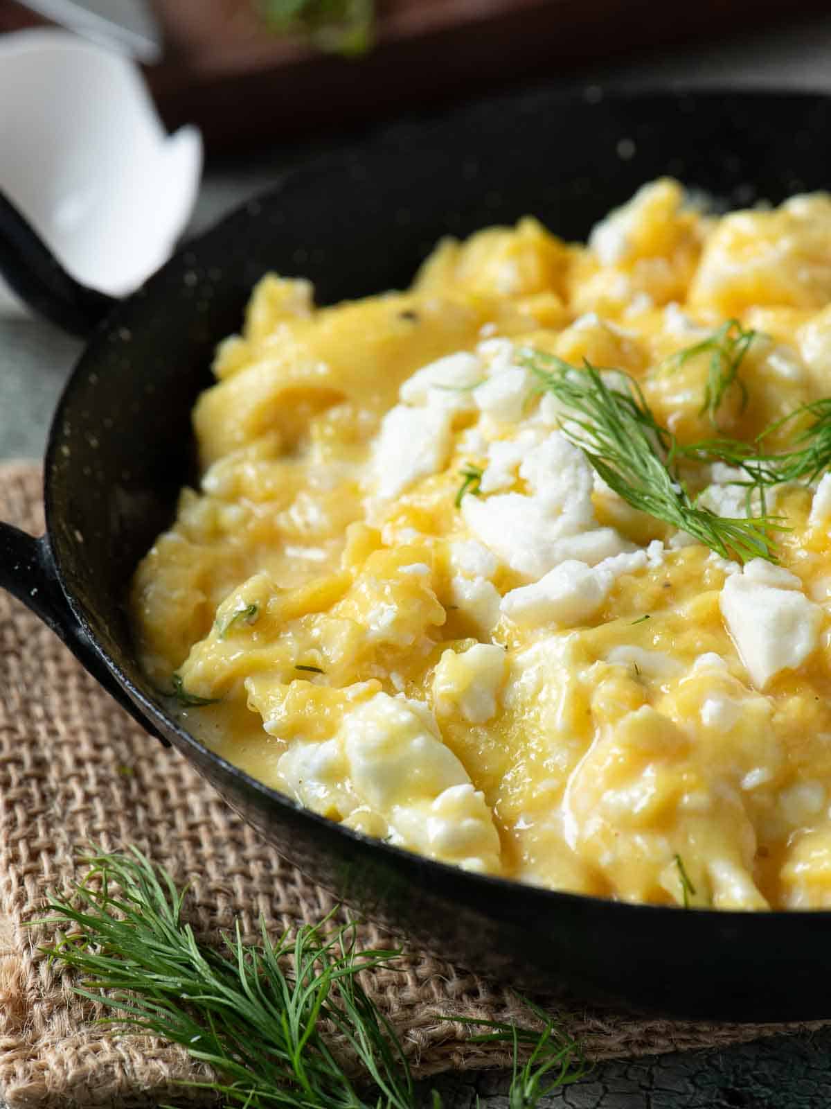 Close up of scrambled eggs in a black skillet.