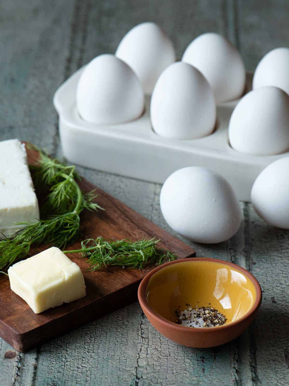 Ingredients for scrambled eggs on a wood board.