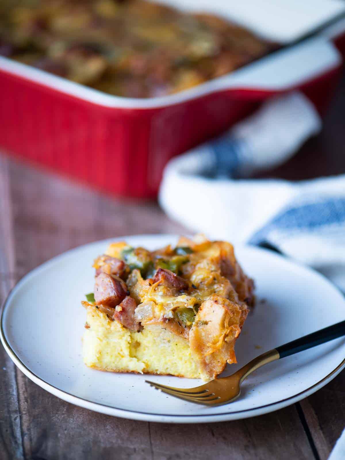 A slice of strata on a plate with a fork to the right.