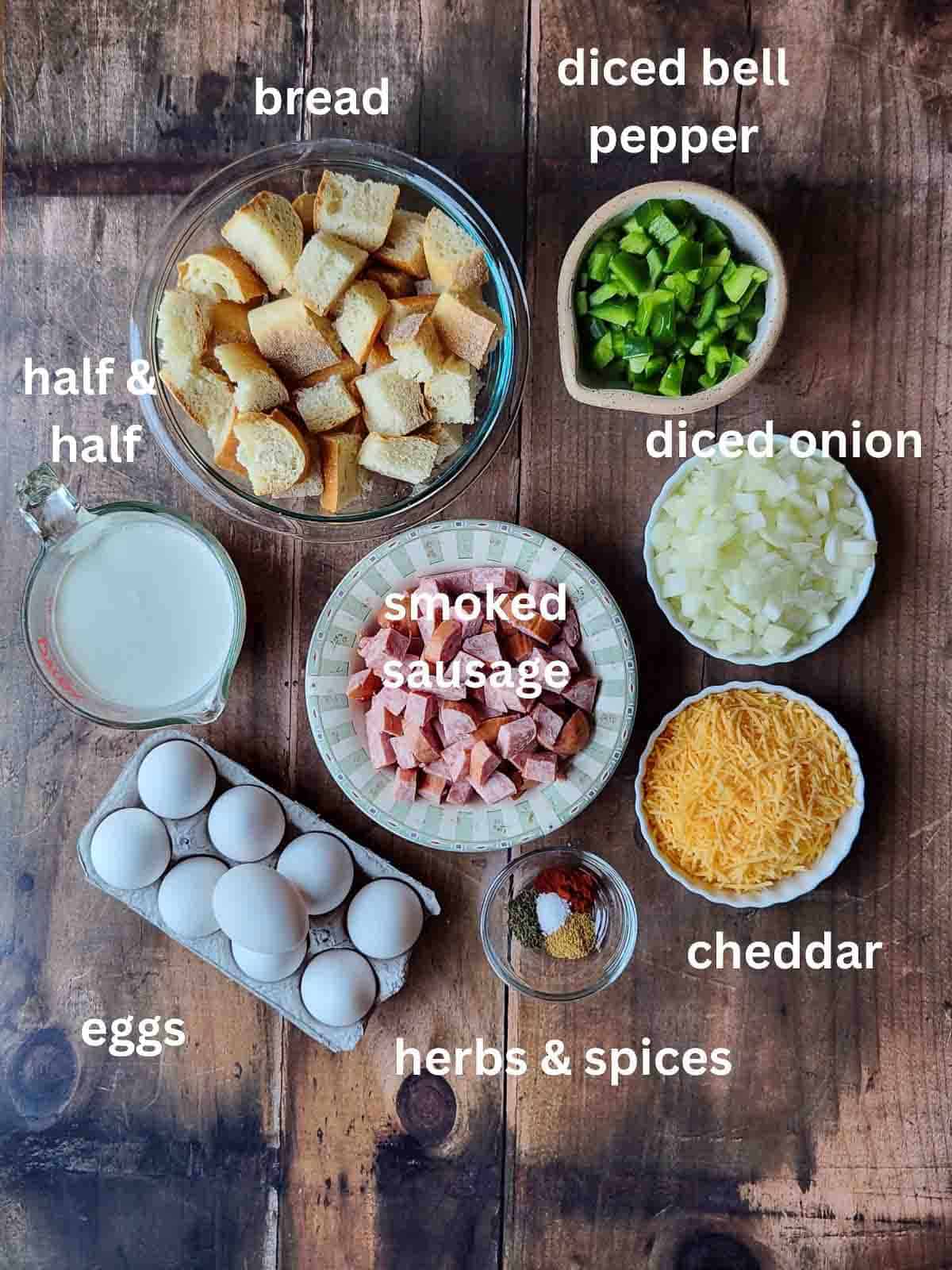 Overhead of ingredients in bowls for a a strata on a wood surface.