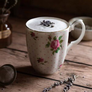 Lavender tea latte in a floral mug on top of a wood surface.
